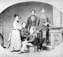 Black and white photograph of five people dressed in Victorian attire. 