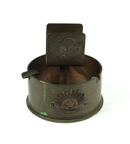 An ashtray and matchbox holder made out of scrap metal from an ammunition shell. 