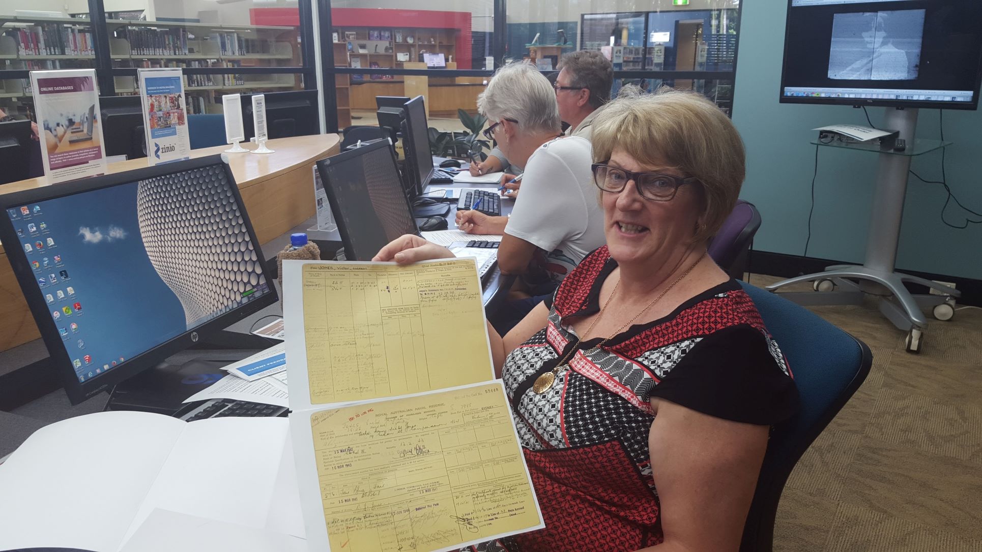 A woman in a computer lab holds a print-out of a historical document.