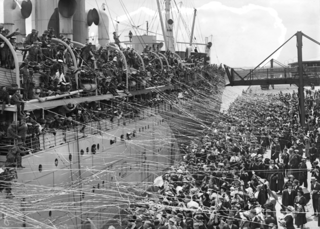People in a boat connected to people on shore connected by streamers