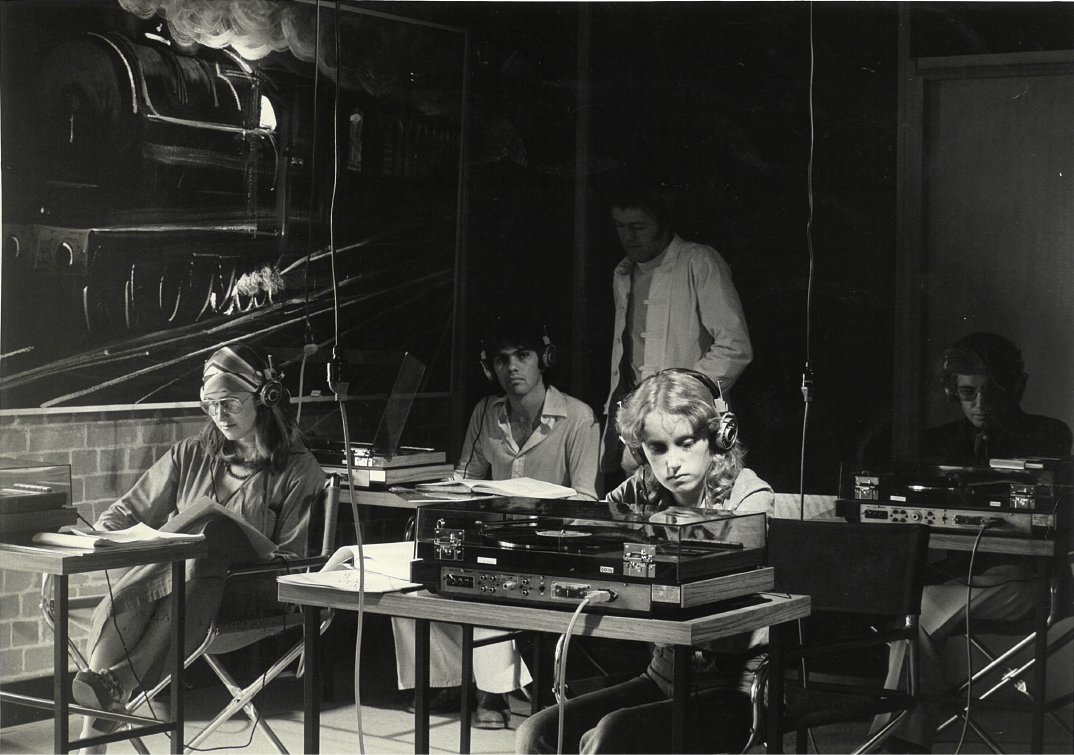 A music studio with 3 people using it. 