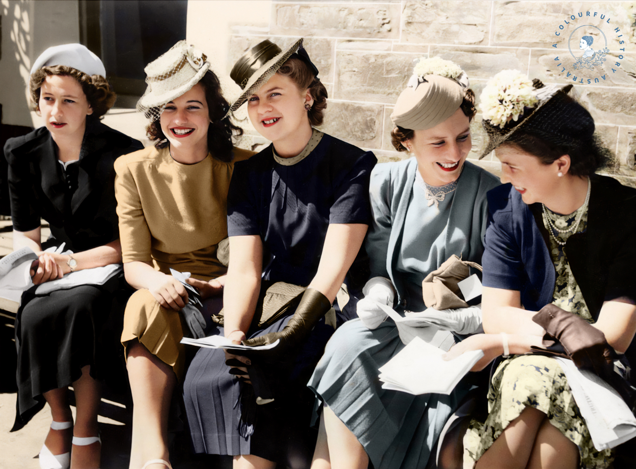 Five women dresses up for the races sitting on a bench smiling