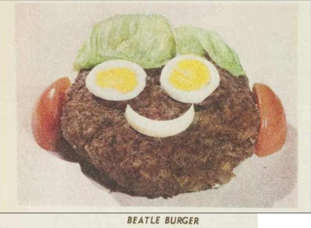 A burger patty with lettuce at the top replicating hair, two egg slices replicating eyes, a piece of onion replicating a smiling mouth and tomato wedges replicating ears. The words 'Beatle Burger' are underneath the image. 