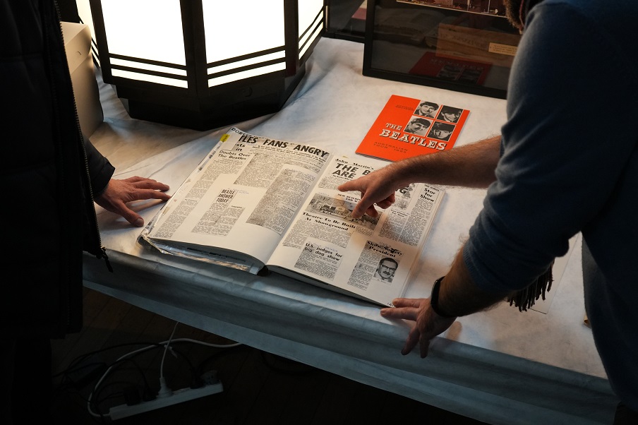 Two men looking at a scrapbook about The Beatles.