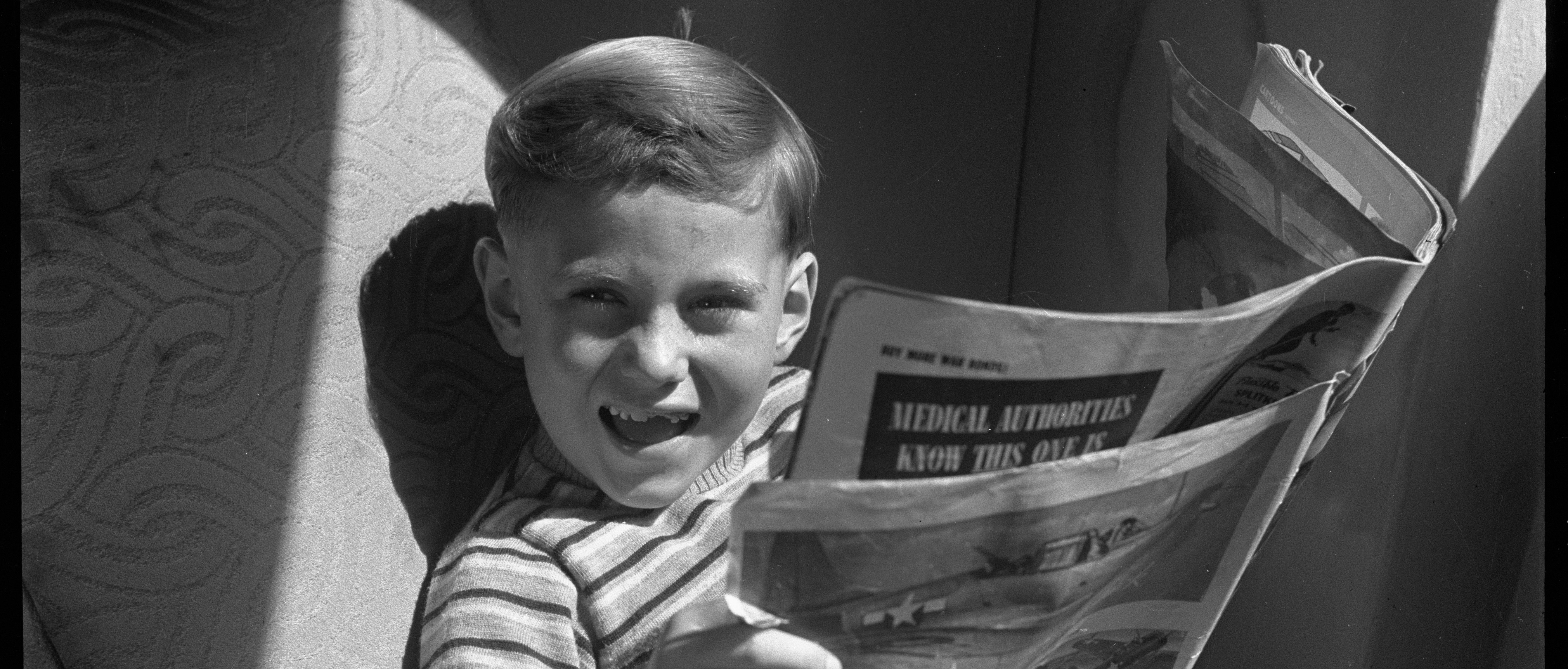 Young child delighted by newspaper