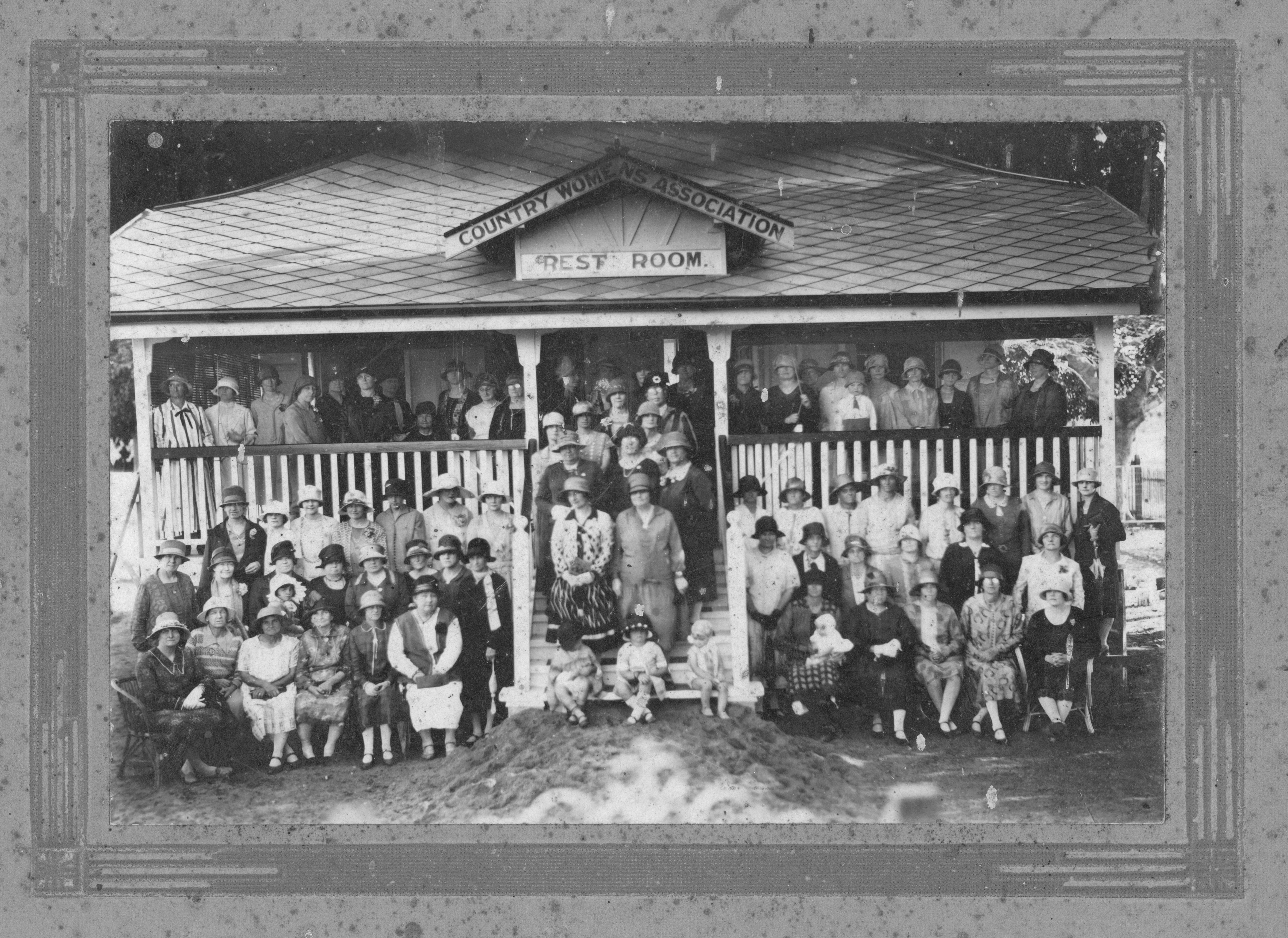 Large group of women standing out the front of a house with a CWA sign