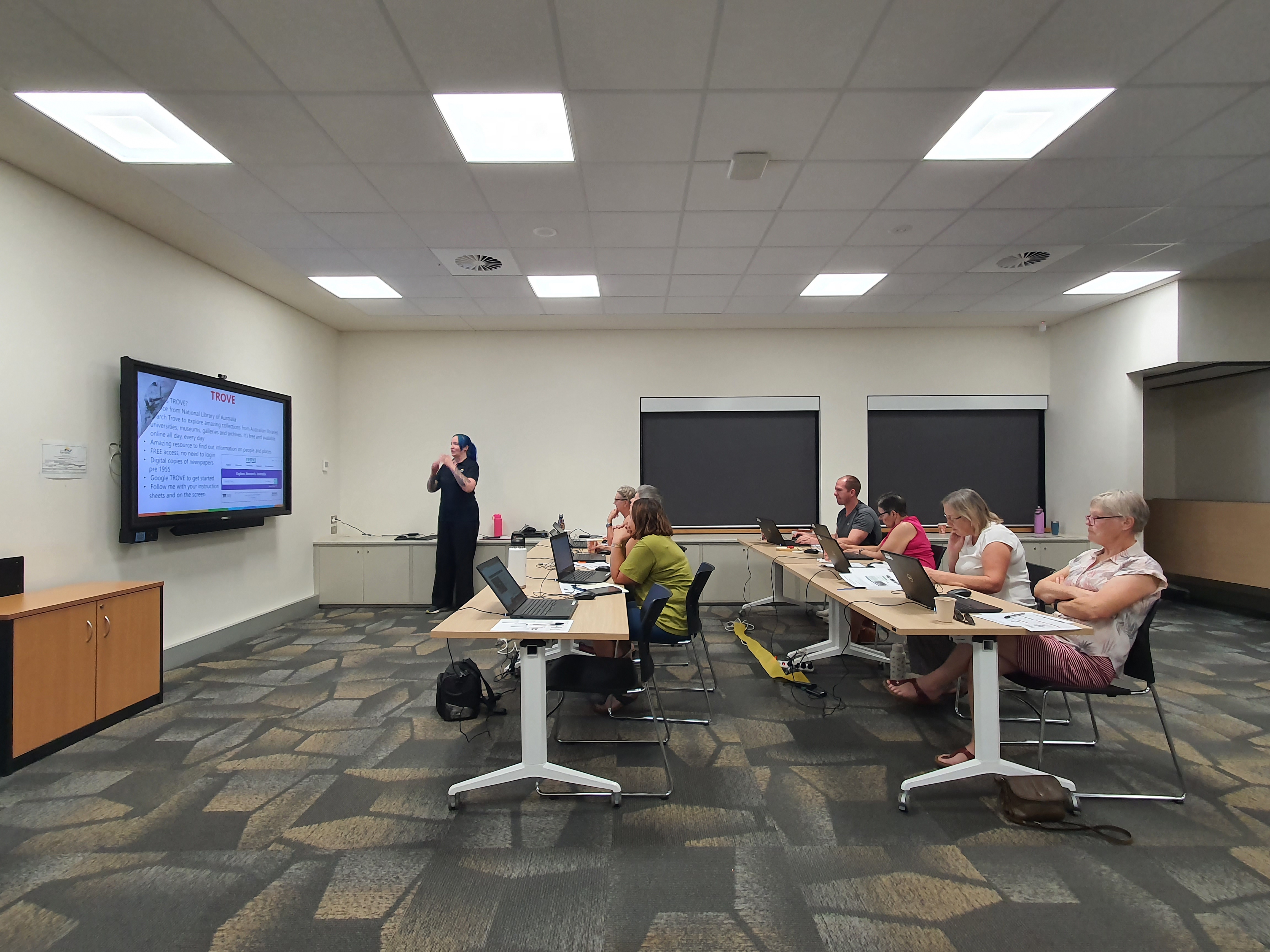 People in a room watching a presentation about Trove.