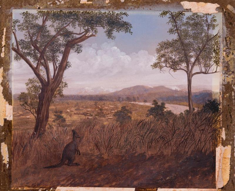 A macropod standing among tall grass on a hill. In the distance there is a large river and a nearby settlement situated on a plain comprised of numerous wooden buildings.
