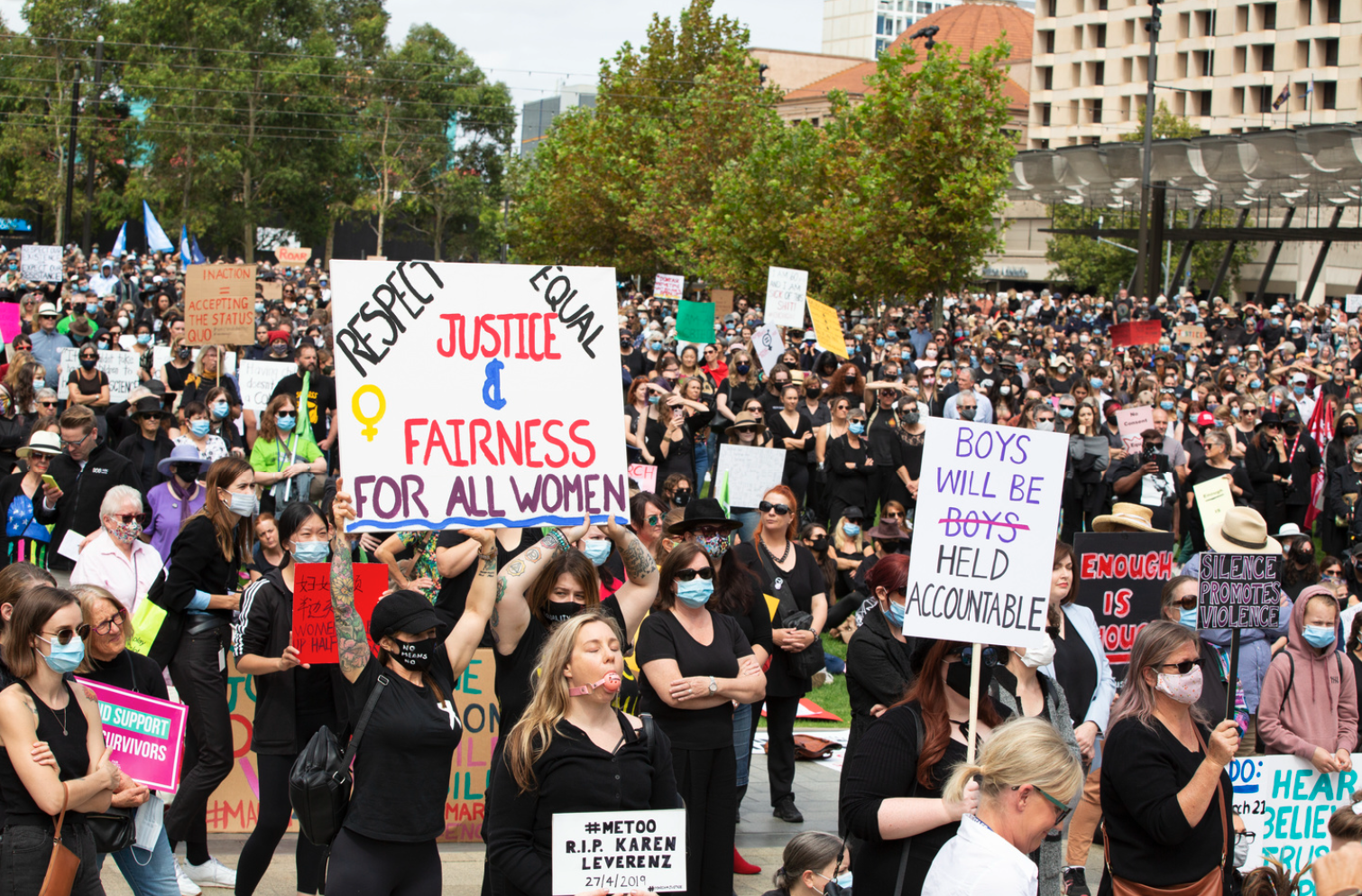 Large group of protestors standing in a square holding signs promoting women's rights. Many of the protestors are wearing face masks.