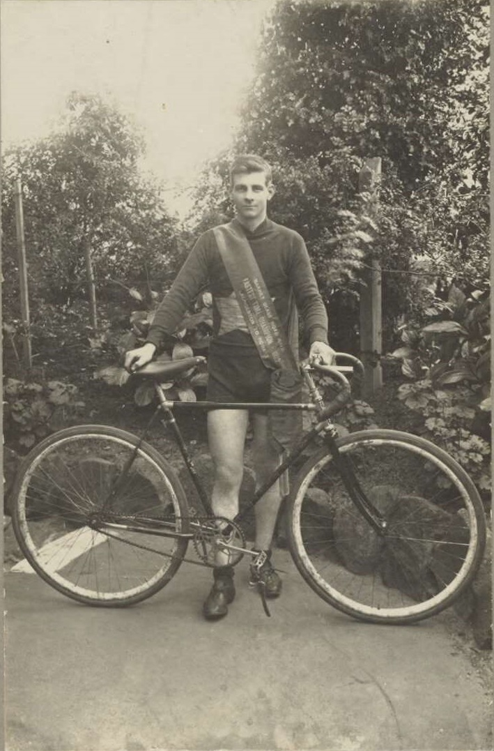 Oppy with his bike stood up in front of him. He is wearing a winners sash.