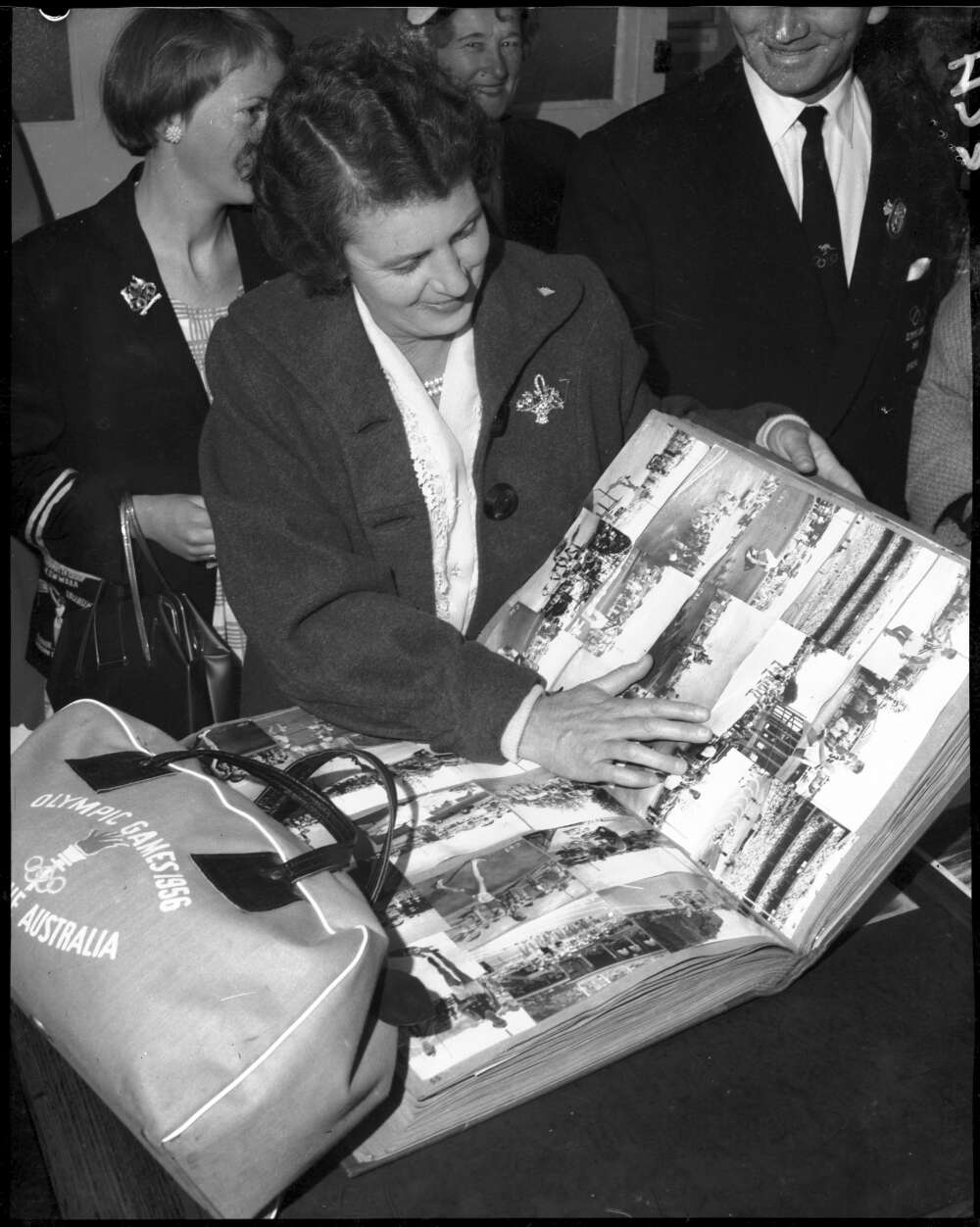 Woman with an large scrapbook containing items related to the Olympic Games.