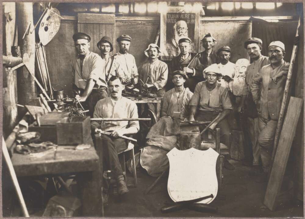 A group of men in a workshop. They are posing for the camera. 