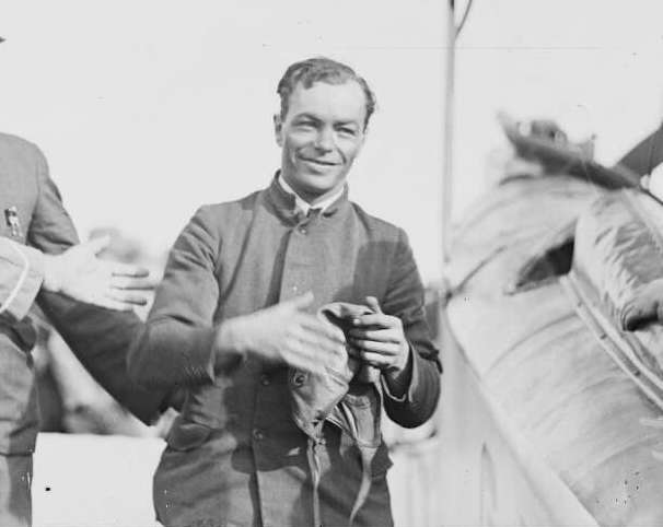 Bert Hinkler walking across a tarmac after landing his plane