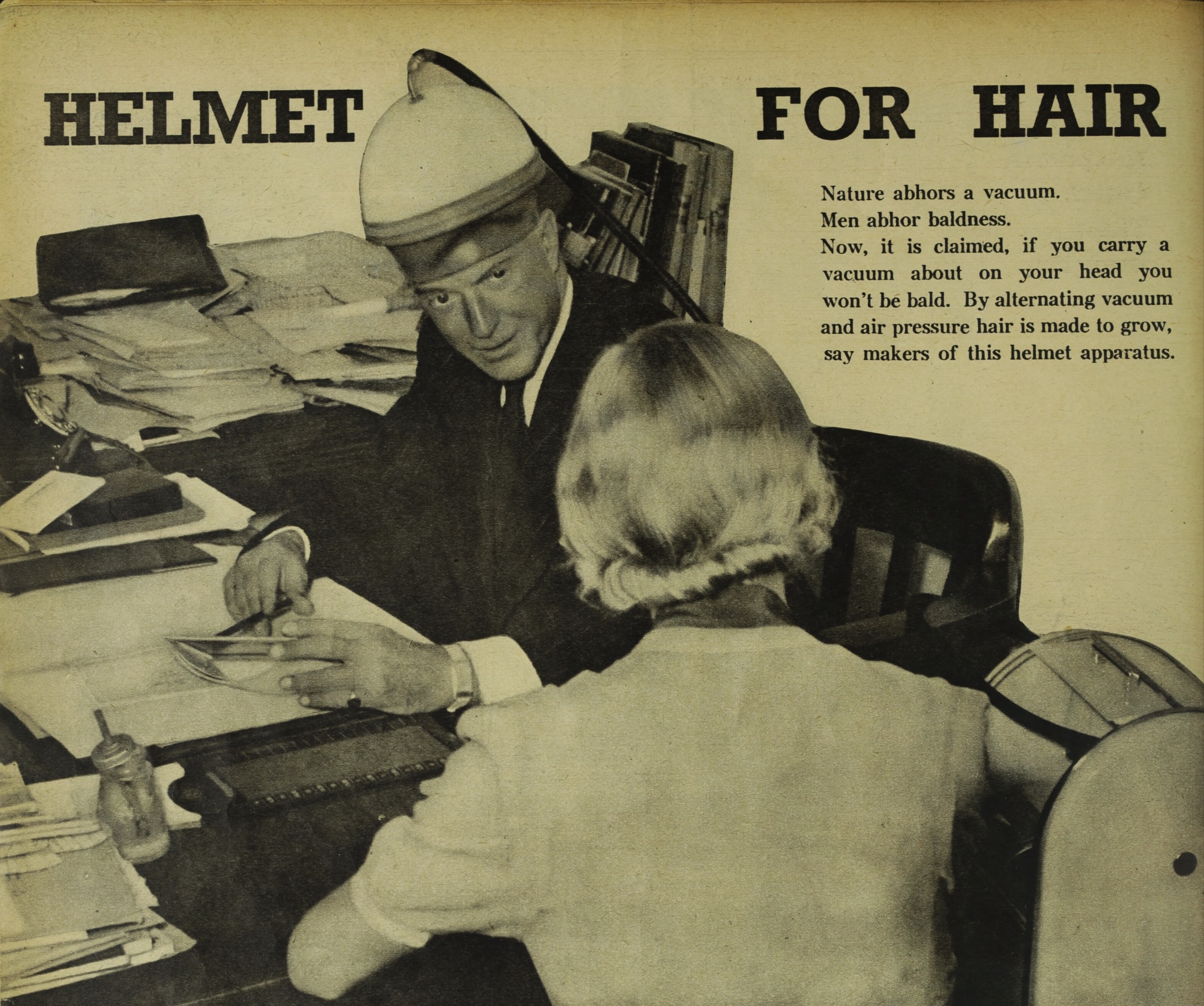 An article titled Helmet for Hair. There is a man sitting at his desk wearing a large vacuum on his head.