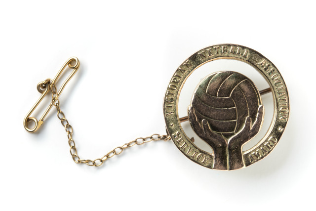 A gold award consisting of a brooch and a medal showing a netball 