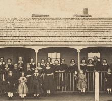 Photograph of  nineteenth century school students standing in rows in front of a building