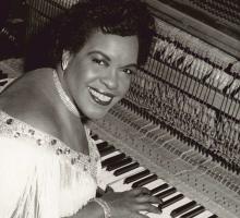 Black and white photo of Trinidadian pianist Winifred Atwell, playing a piano