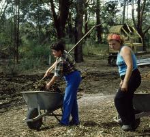 Two people with gardening equipment spreading mulch in rainforest section at the North Coast Regional Botanic Garden