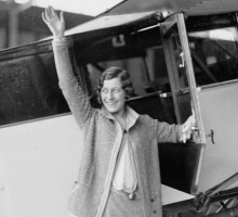 English aviatrix Amy Johnson waving and opening the door to her plane. 