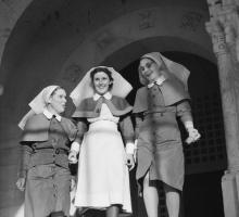 Three nurses walk down steps of a British War hospital. The photo is black and white.