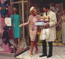 Woman dressed in 1960s outfit shopping with a male shop assistant