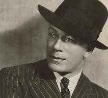Man wearing a stripped suit and fedora hat
