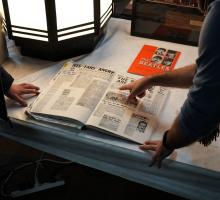Two men looking at a scrapbook about The Beatles.