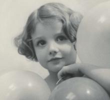 A young girl holding three ballons