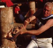 A man competing in a woodcutting competition mid-swing. 